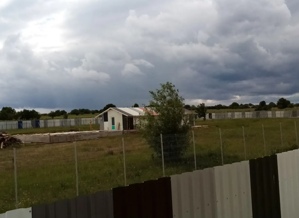 The new fence around the plot, the first building in the distance.