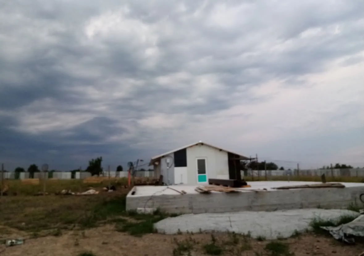 A fresh concrete base in front of the first building under a stormy sky.